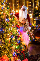 little Girl and Santa decorate the Christmas tree