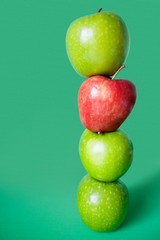 Red and green apples balancing over colored background
