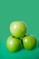 Close-up of green apples in pyramid stack over colored background