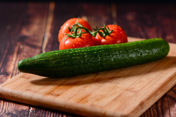 Isolated cucumber. One whole cucumber isolated on black background with clipping path. Vine tomatoes on black background. Tomato  with drops isolated on wooden, horizntal