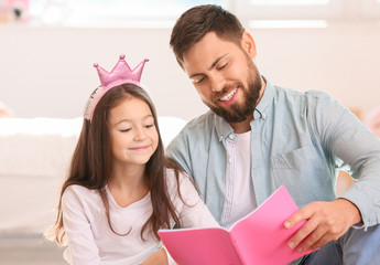 Father with little daughter reading book at home