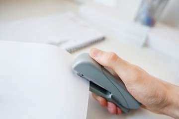 Close-up of man's hand stapling paper in office