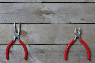 nippers and pliers with red handles on a wooden background. copy space.