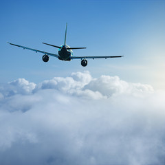 Flying of the passenger plane above the clouds and mountains.