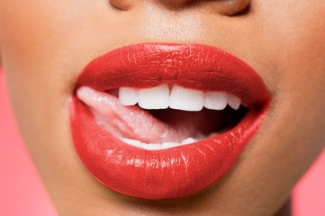 Obraz premium Cropped image of woman licking red lipstick
