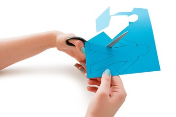 Woman's hand cutting a paper stick figure over white background