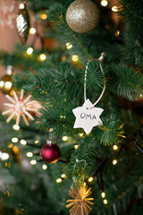 christbaumanhaenger selbstgemacht aus salzteig mit der aufschrift oma im weihnachtsbaum haengend hochformat