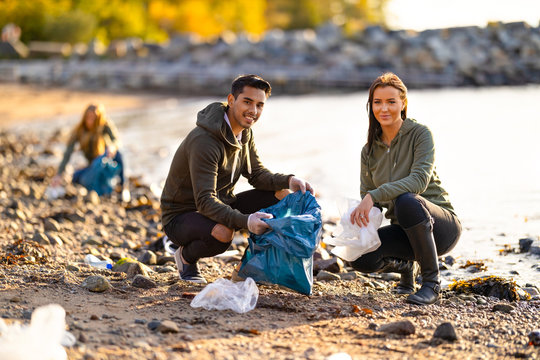 Portrait of smiling environmental protection volunteers cleaning beach