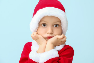Cute little boy in Santa costume on color background