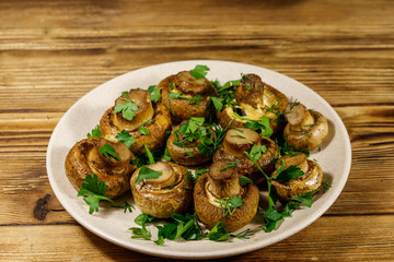 Baked mushrooms in plate on wooden table