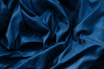Closeup classic blue macro texture of shiny smooth material fabric or clothing. Toned trendy 2020...