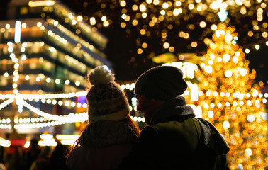 Fototapeta premium The couple are looking at the decorated Christmas market in the evening