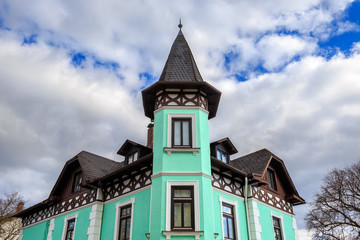 Fototapeta na wymiar Historical traditional colorful corner house in Starnberg, Bavaria, Germany - part of the facade. Stormy rain clouds and a V-shaped patch of blue sky.