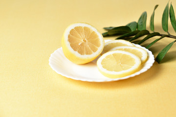 Juicy lemon on a white plate on a yellow background