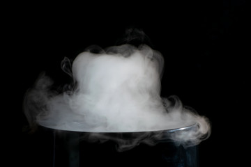 Puffs of white smoke randomly rising rise from the chimney partially flowing down its edges on a black background