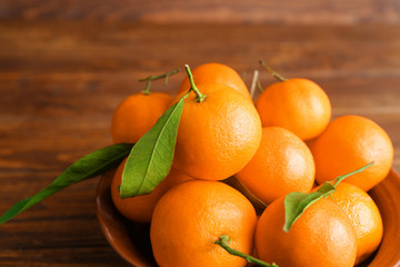 Bowl with sweet tangerines on wooden table, closeup