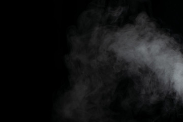 Beautiful puffs of white smoke randomly mixing slowly fill the blackness of the frame