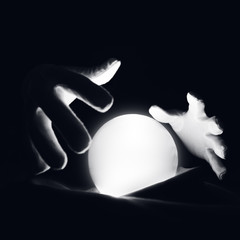 Spiritual session predicting the future. Open hands in white gloves over a luminous crystal ball.