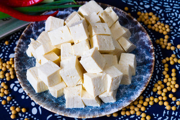 Sliced tofu cubes in a plate with soy bean on the side
