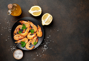 raw prawns waiting for the cook to grill, in a black plate with herbs and spices on a stone background with copy space for your text