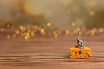 A toy mouse sits in cheese on a wooden starry background, a symbol of 2020.