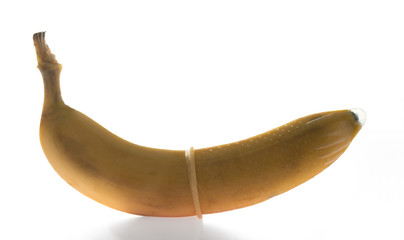 Condom on a ripe yellow banana isolated on white background.