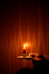 Candle light shining in the dark against wood background. Power outage, blackout concept.