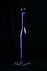 Elegant blue bottle of expensive wine gift with drops of water on a black background isolated