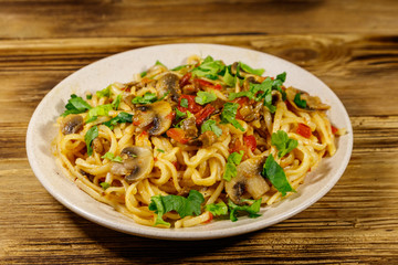 Pasta with mushrooms and tomato sauce on wooden table