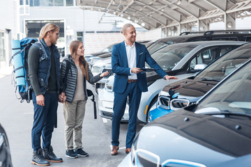 Young adult man and woman choosing rental car for travel