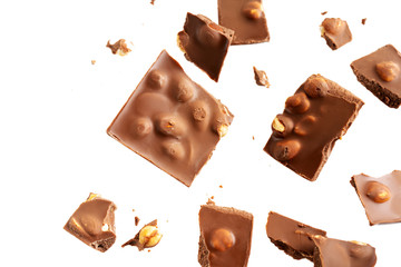 Flying in the air broken bar of milk chocolate with nuts and flakes isolated on white background.  Chocolate pieces levitation concept.
