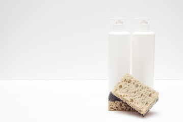 Detergent bottle and sponge on white background with copy space.
