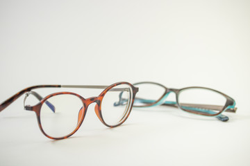 Two pairs of modern glasses isolated in a studio shot one with black and turquoise colored frames and a blue blocking pair prescribed from a profession optometrist with isolated white background 