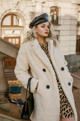 Outdoor autumn, winter fashion portrait of young elegant confident woman wearing trendy white faux...