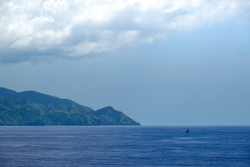 Fototapeta na wymiar The hazy and mountainous coastline of the Caribbean Island of Haiti as a cruise ship sails by.