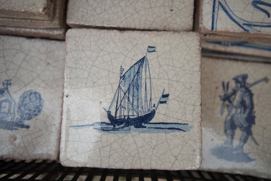 Light ceramic tiles with drawings of blue in Spain. Photography of close upbeige stone stripes with a texture of chaotic lines with a blue ink pattern of sailing ship.