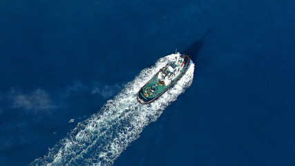 Aerial drone top down photo of tug boat cruising Mediterranean port