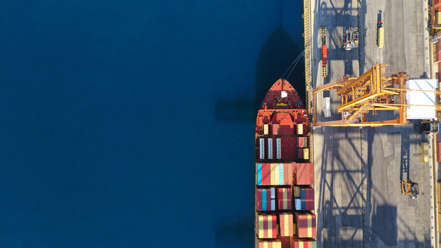 Aerial drone top down photo of industrial cargo container tanker ship carrier docked in commercial port terminal