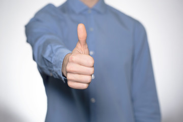 Close up of beautiful young man in a blue shirt  showing  like on white background. Hand like.  Gesturing hands stock image 