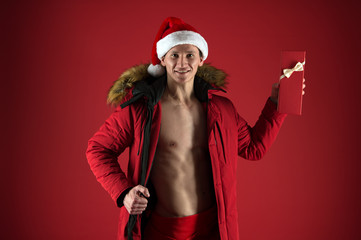 gift with love. new year party for adult. macho man in santa hat and puffer jacket. sexy santa...
