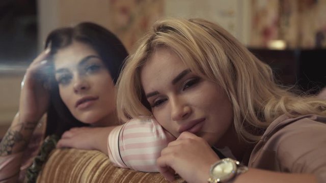 Portrait of two passionate models relaxing on bed with pillow in luxury room