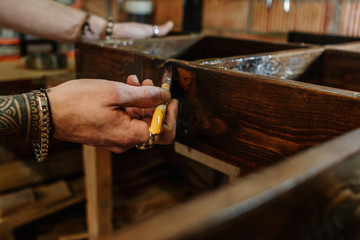 Hands of a carpenter brushing a wooden furniture at craft workshop