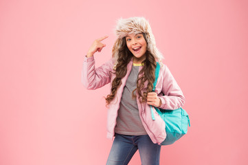 Quality School. small happy girl back to school. winter holiday vacation. kid warm clothes pink background. happy child earflap hat. schoolgirl with bag go home. end of school year. no more exams