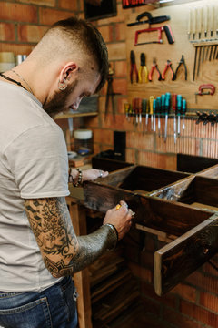 Craftsman artist applying varnish paint on a wooden furniture at craft workshop