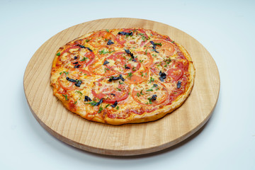 Pizza with slices of sausage, cheese, olives and tomatoes cut into rings. The pizza is cut into pieces, one pushed away from the others.