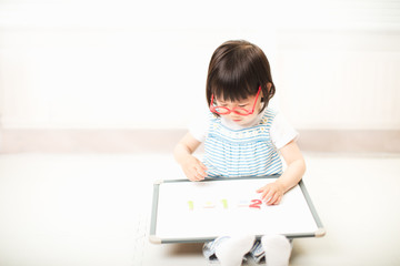 Naklejka premium toddler girl using white board learning math at home