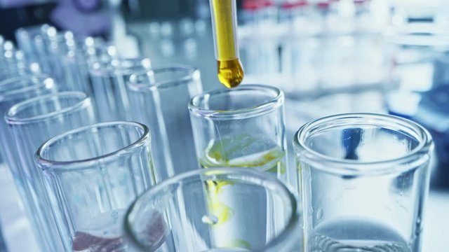 Pharmaceutics Laboratory: Pipette Dropping Yellow Liquid into Test Tubes, Medical Research, Analysis. Scientific Lab; Dropper Fills Sample Tubes with Innovative DNA Study Solution. Close-up Macro