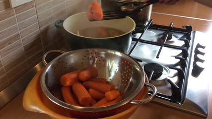 Boiling carrots inside a pot, on a gas burner, at a restaurant kitchen