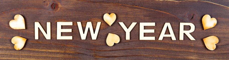Happy new year letters with hearts on a wooden background, web banner