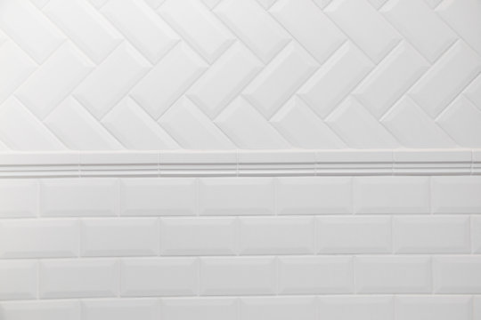 Bathroom wall tiled in scandinavian style with white grouting. Connection two different tile layouts herringbone and brick wall © vladdeep